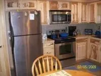 Kitchen with stainless steel appliances, light wood cabinets, and a microwave above the stove.