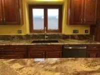Kitchen with dark wood cabinets, granite countertops, and a window above the sink.