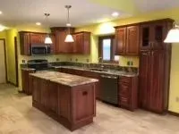 Kitchen with dark wood cabinets, granite countertops, and island with a light-colored floor.