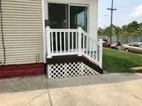 White deck with railing and lattice, leading to a sliding glass door.