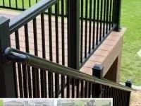 Black deck railing with vertical balusters; brown deck boards; green grass background.