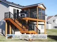 Wooden deck with stairs, a screened-in porch, and a built-in grill attached to a house.