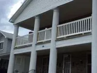 Two-story house with white columns, balconies, and gray siding.