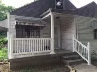 White house with small porch, awning, and steps.