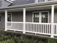 White-railed porch on gray-sided house with white columns and windows.