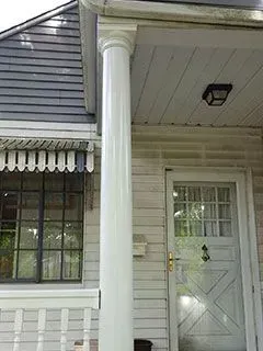 White column supports a porch roof; a front door with glass panes is visible.