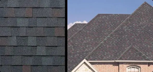 Close-up of roofing shingles next to a house roof under a blue sky.