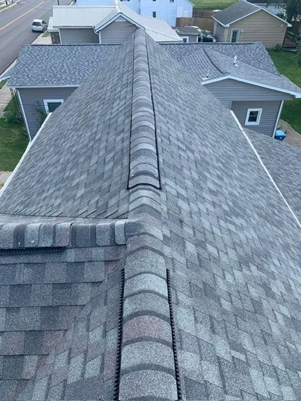 Overhead view of a house roof with gray shingles and a ridge cap.