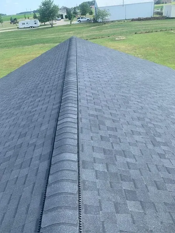 Dark gray asphalt shingle roof, ridge cap along center, view from above.