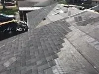 Overhead view of a roof with partially installed gray shingles, showing new and old areas.