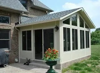 Sunroom addition with beige siding and large windows, attached to a brick house. A potted plant sits outside.