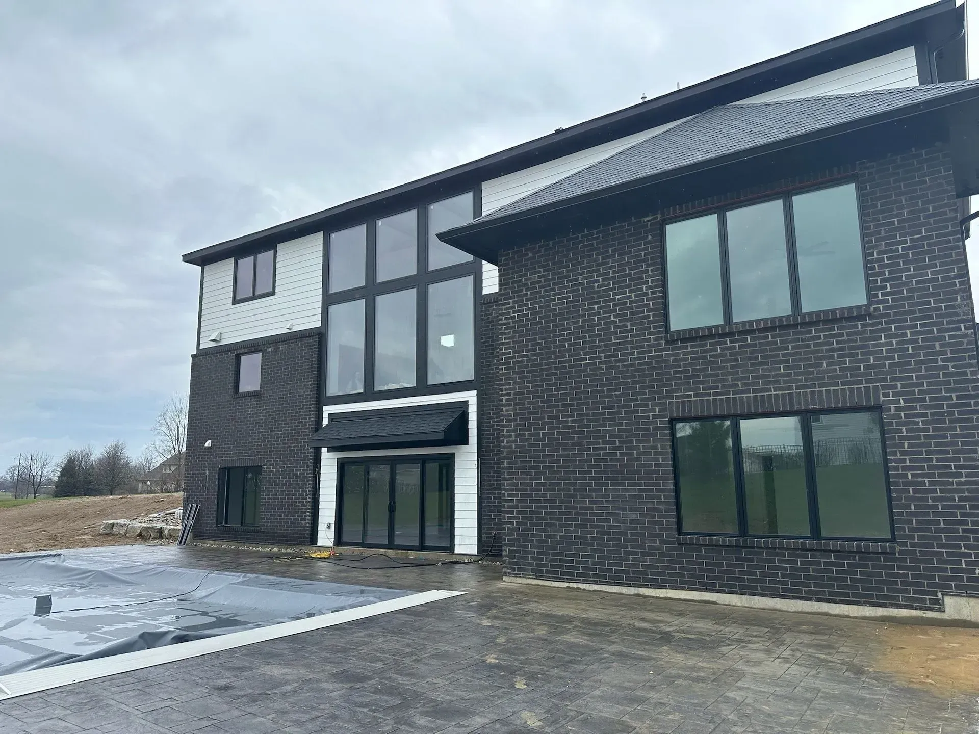 Modern two-story brick house with large windows under a cloudy sky.