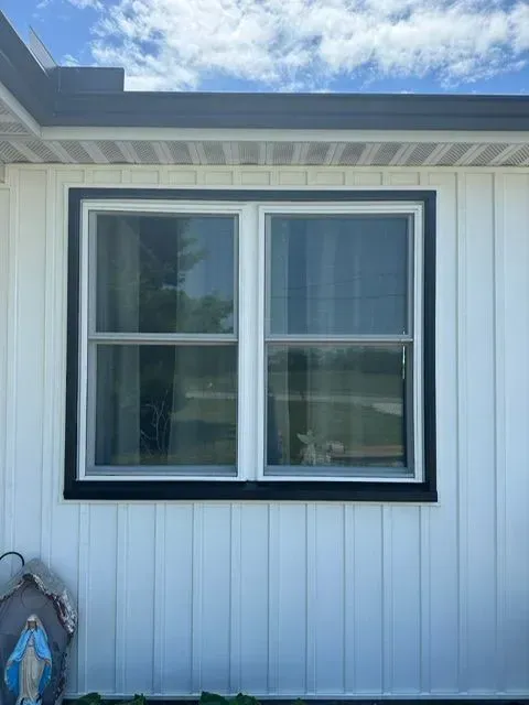 White house with a double-hung window framed in black trim.