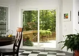 Interior view: Sliding glass door to a deck surrounded by greenery, black and white checkered floor.