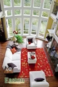 Living room with red rug, white furniture, and large arched windows overlooking greenery.