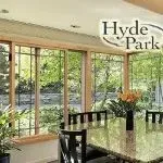 Dining room with large windows, wooden frames, overlooking greenery, table with chairs.