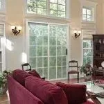 Living room with large sliding glass door, red couch, and high windows.