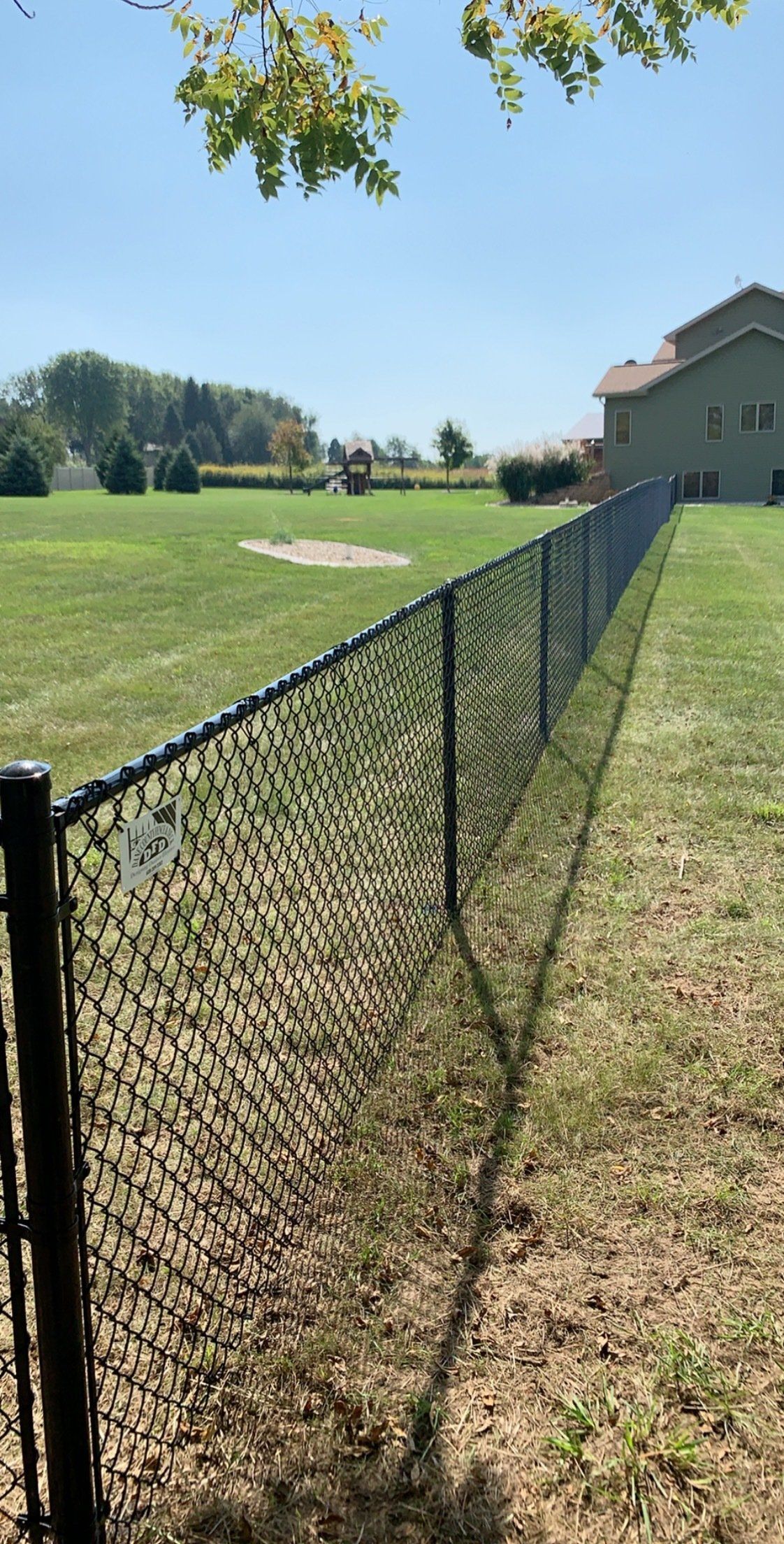 A chain link fence surrounds a lush green field.