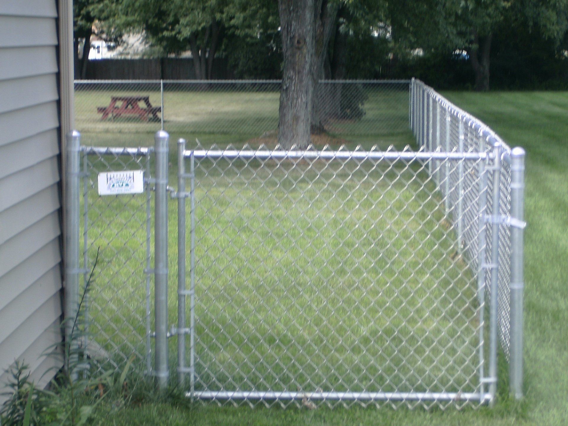 A chain link fence surrounds a yard with a picnic table in the background