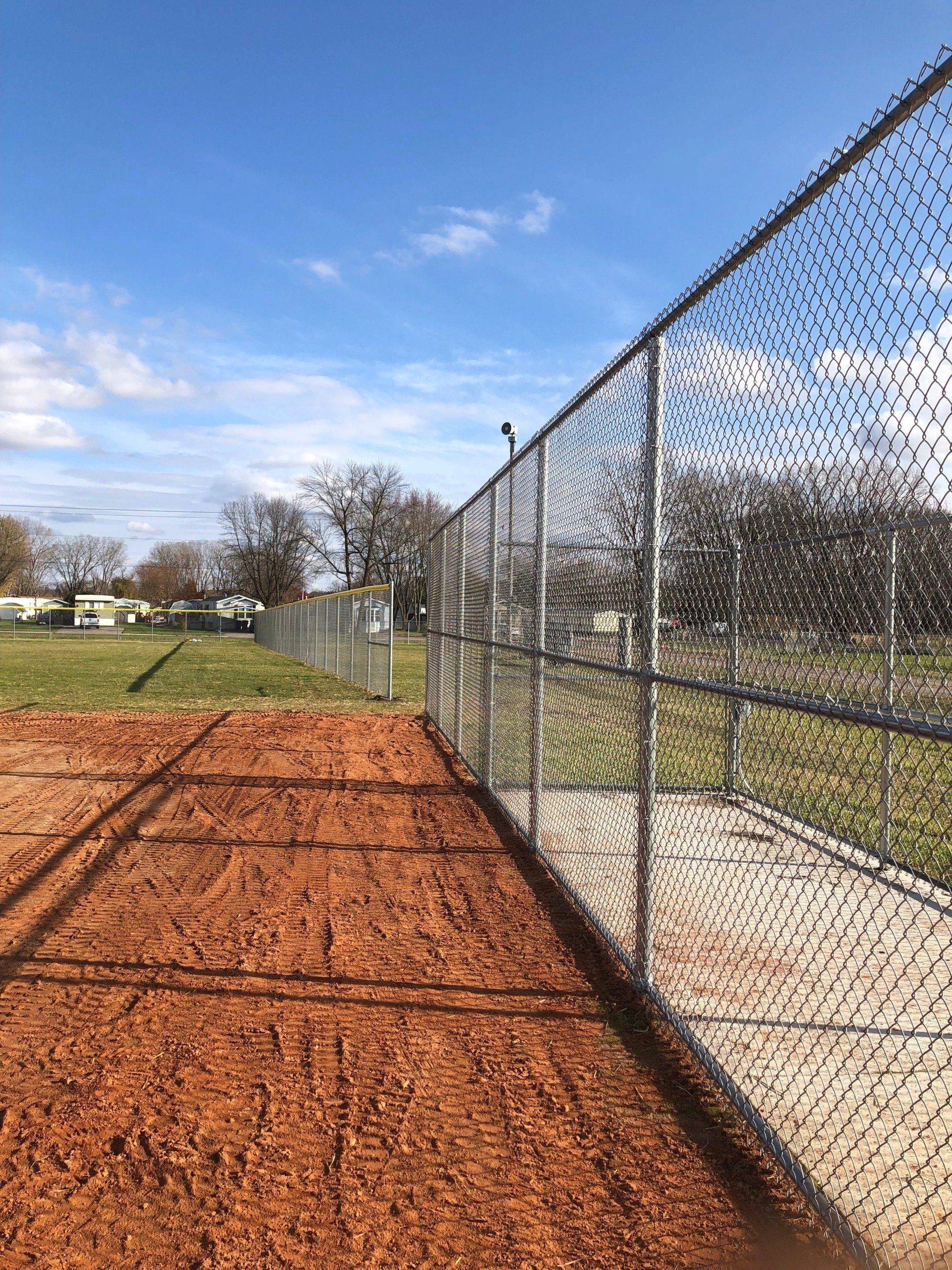 A chain link fence surrounds a baseball field.