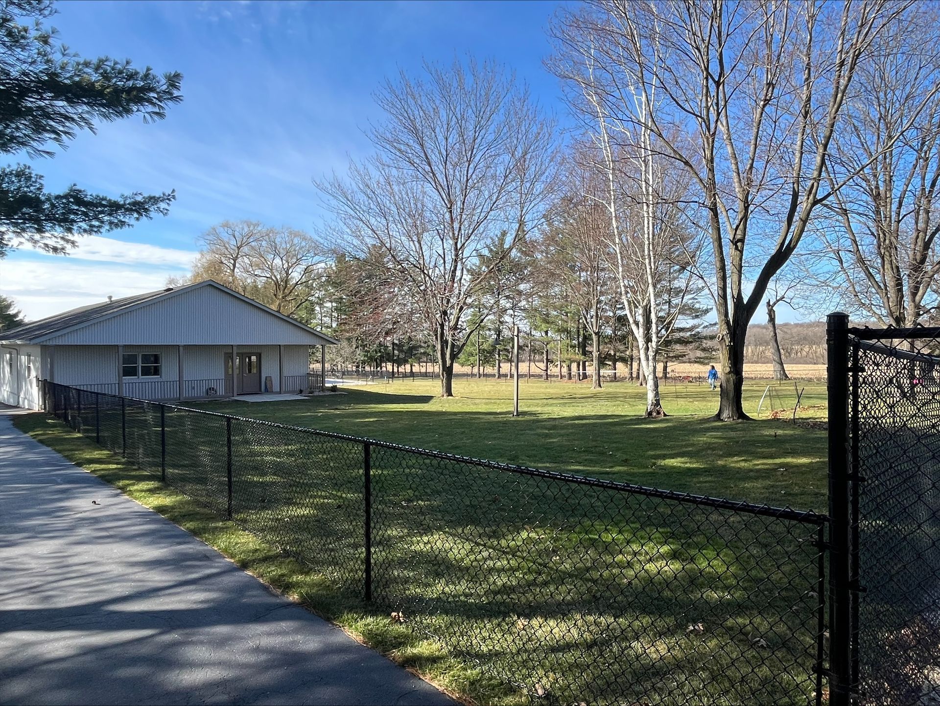 A chain link fence surrounds a house in a park.