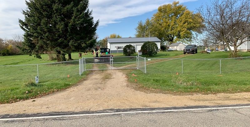 A dirt road leading to a house with a fence around it.
