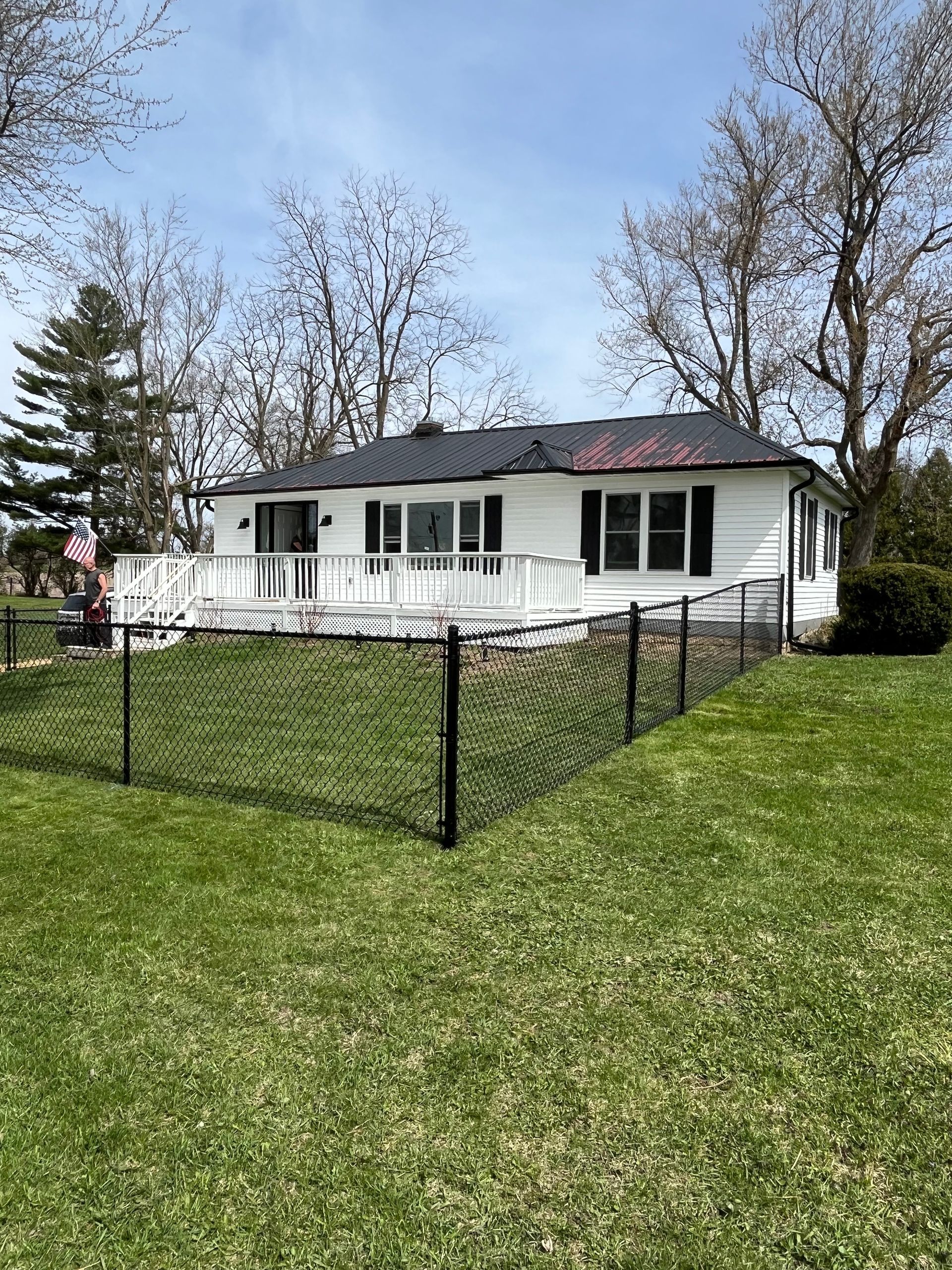 A white house with a black chain link fence in front of it.