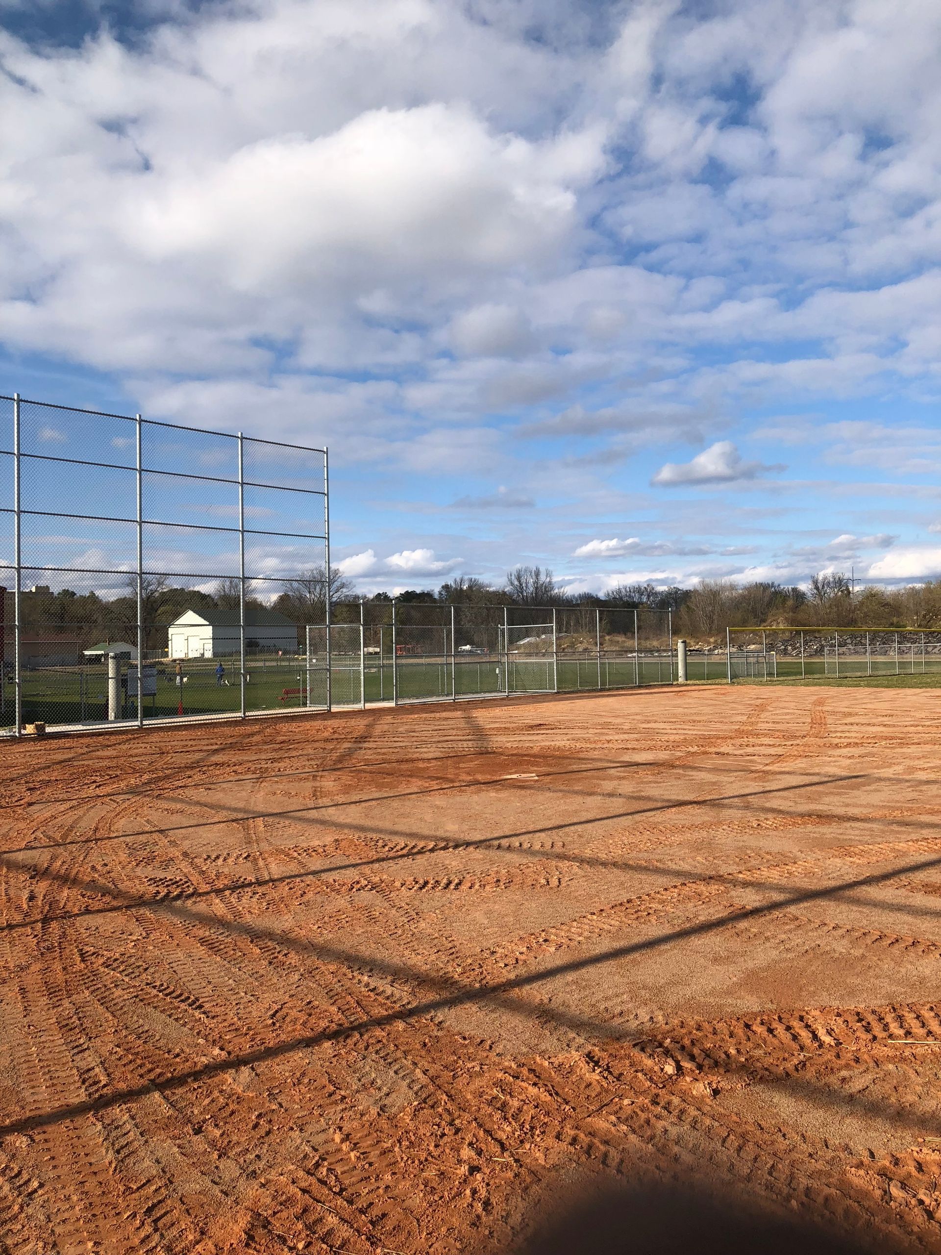 A baseball field with a fence and a blue sky in the background.