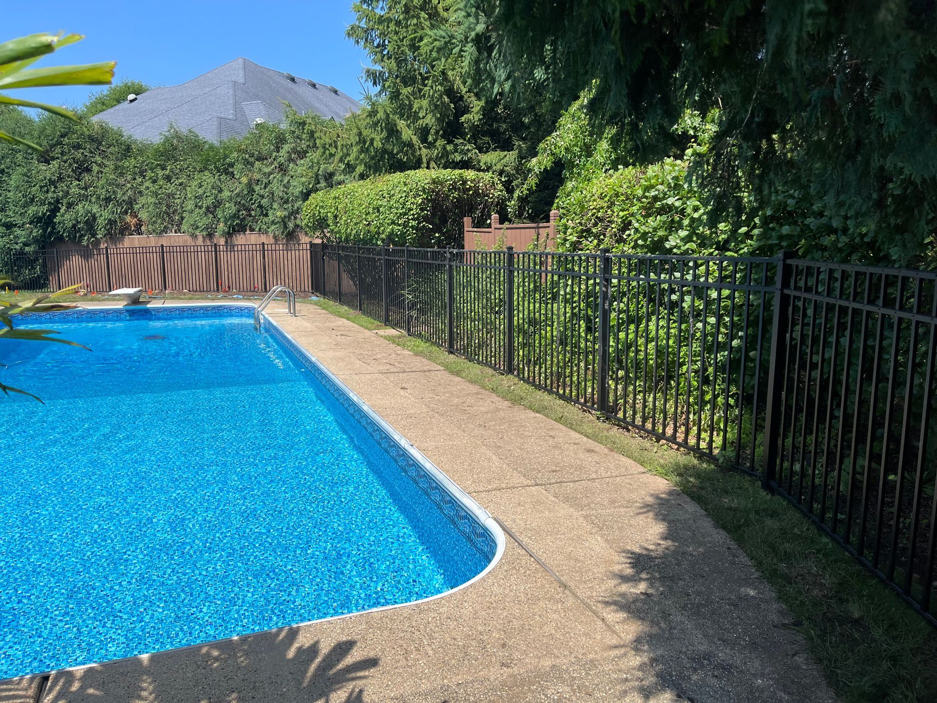 A large swimming pool surrounded by a metal fence in a backyard.