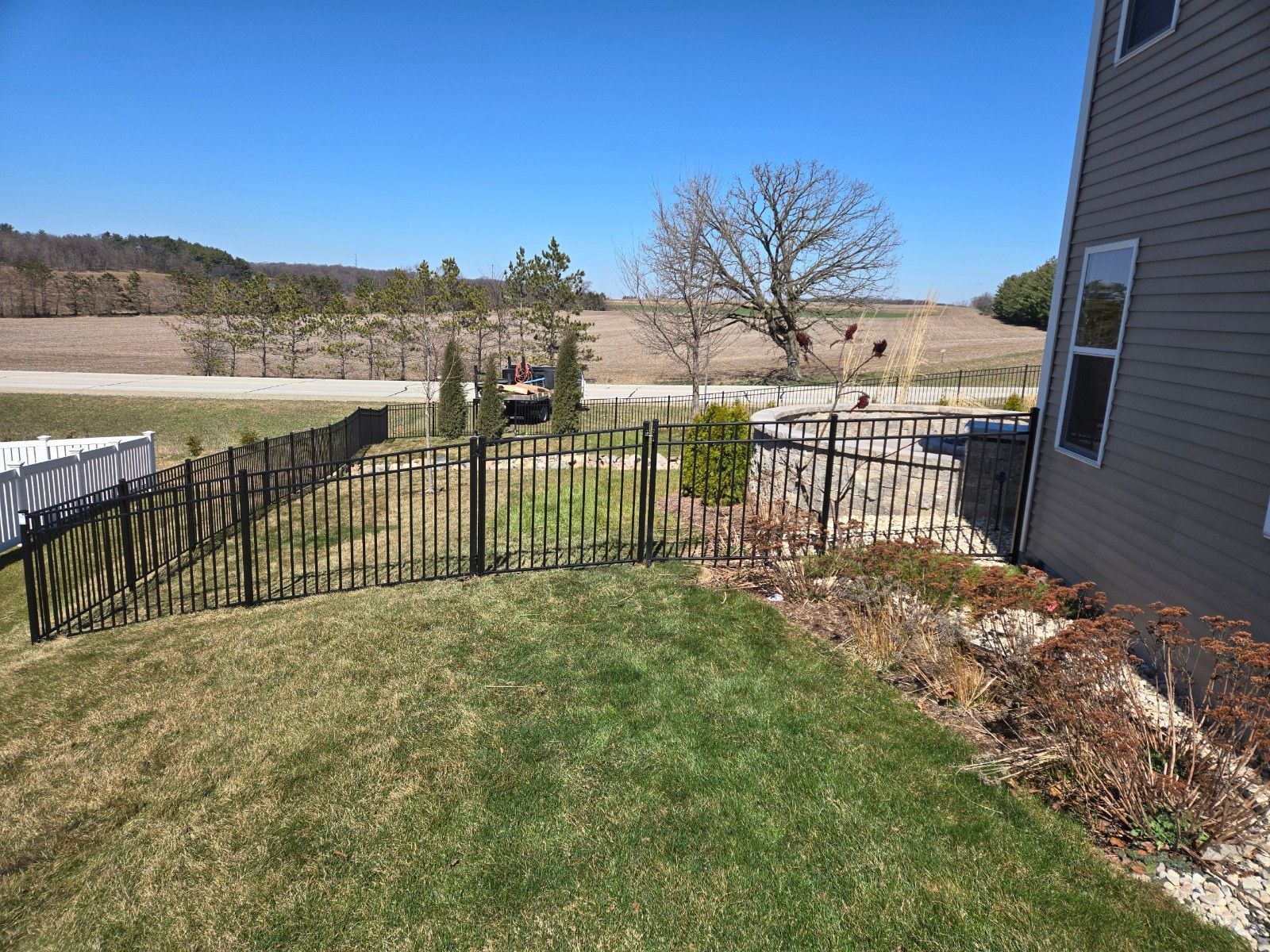 A backyard with a fence and a house in the background.
