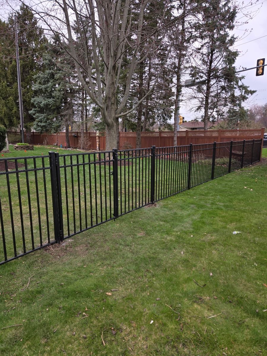 A black metal fence surrounds a lush green yard.