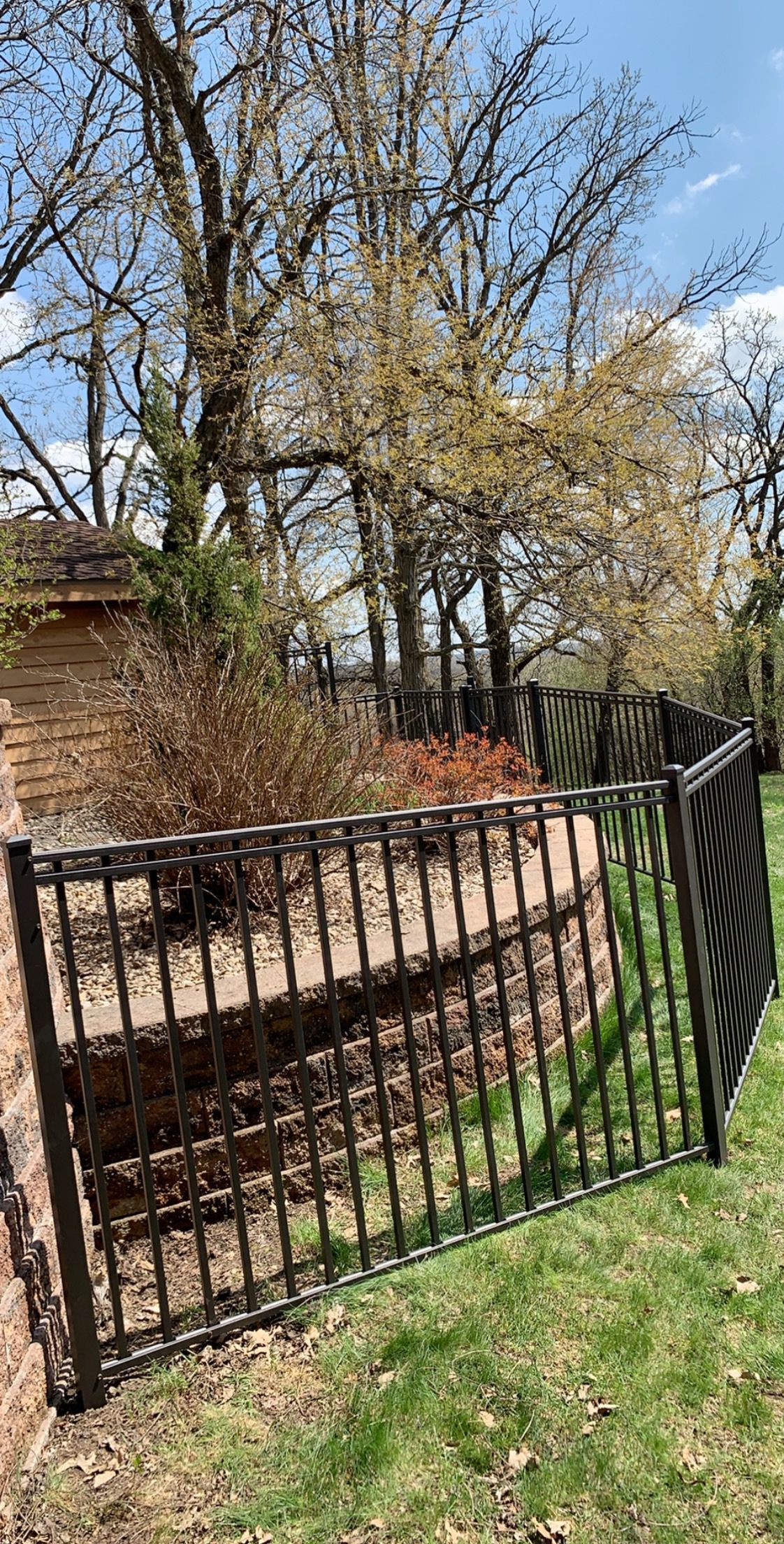 A wrought iron fence is sitting in the middle of a lush green field.