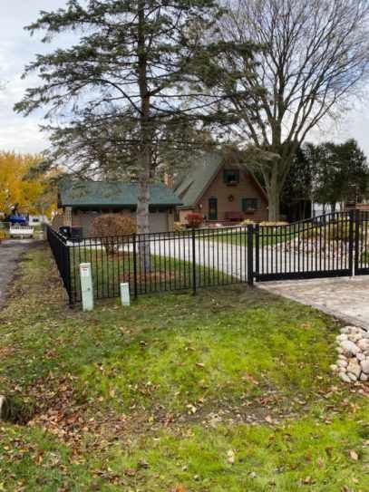 A house with a fence around it and a driveway leading to it.
