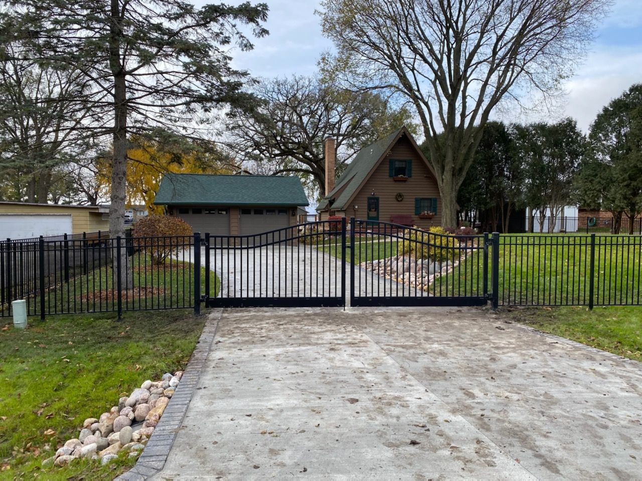 A black metal fence is surrounded by trees in a yard.