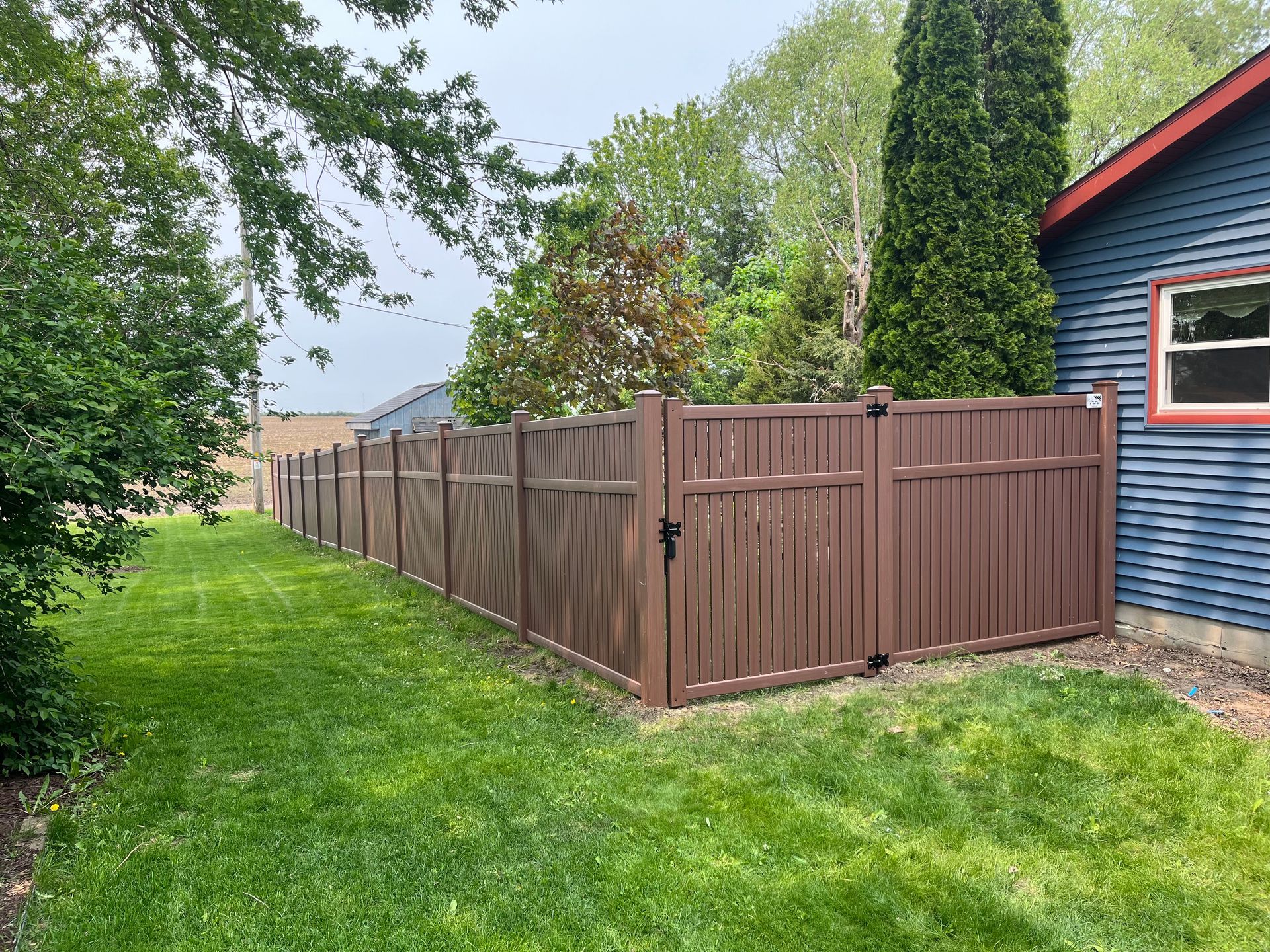 There is a wooden fence in the backyard of a house.