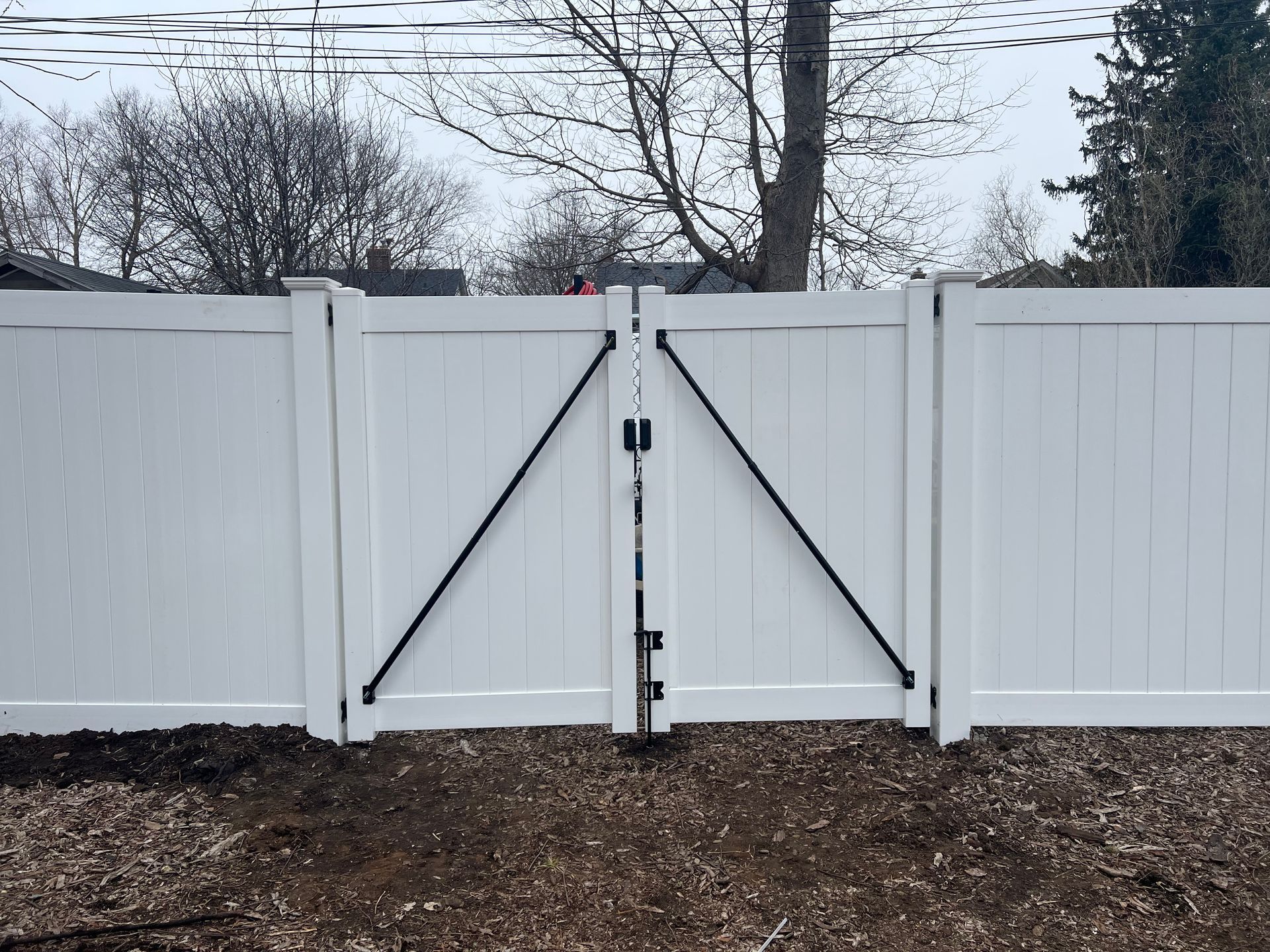 A white fence with a black gate attached to it.