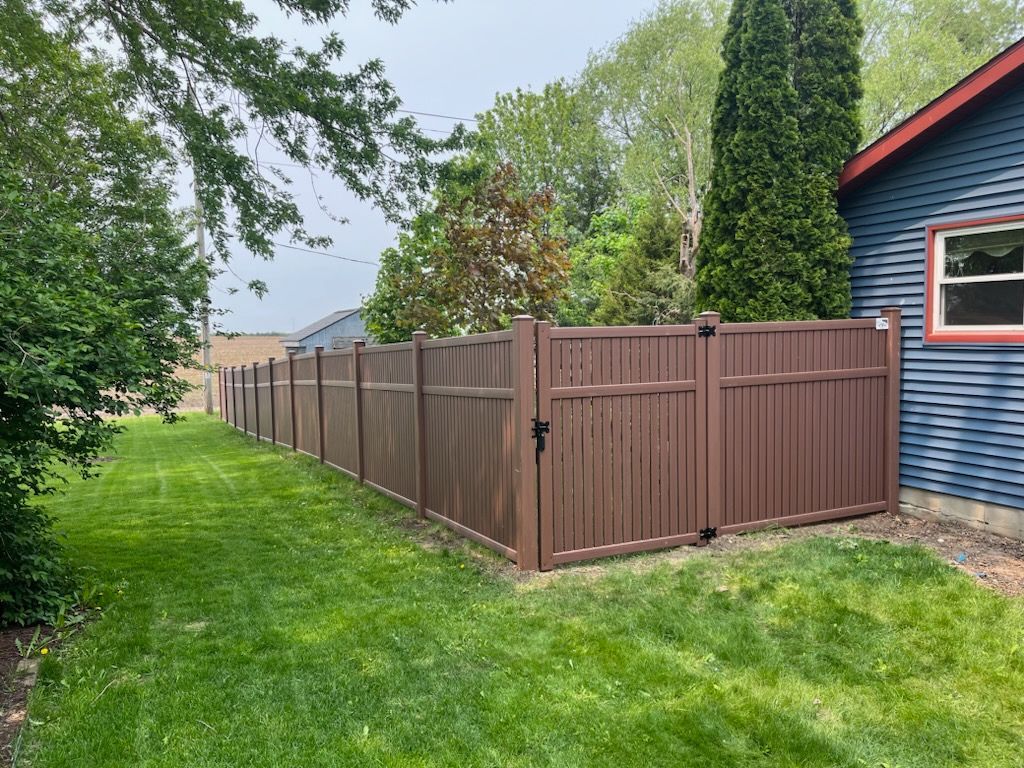 A brown fence is in the backyard of a house.