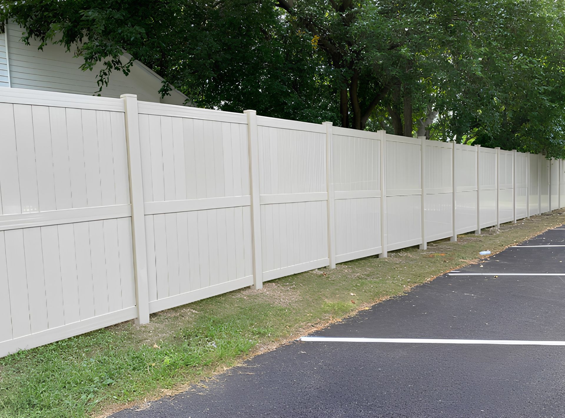 A white fence along the side of a parking lot