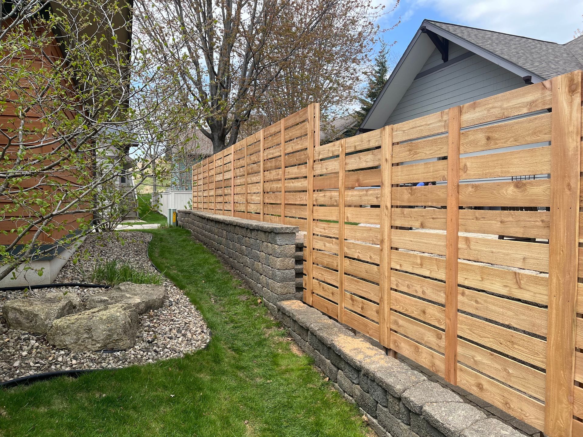 A wooden fence is in the backyard of a house.