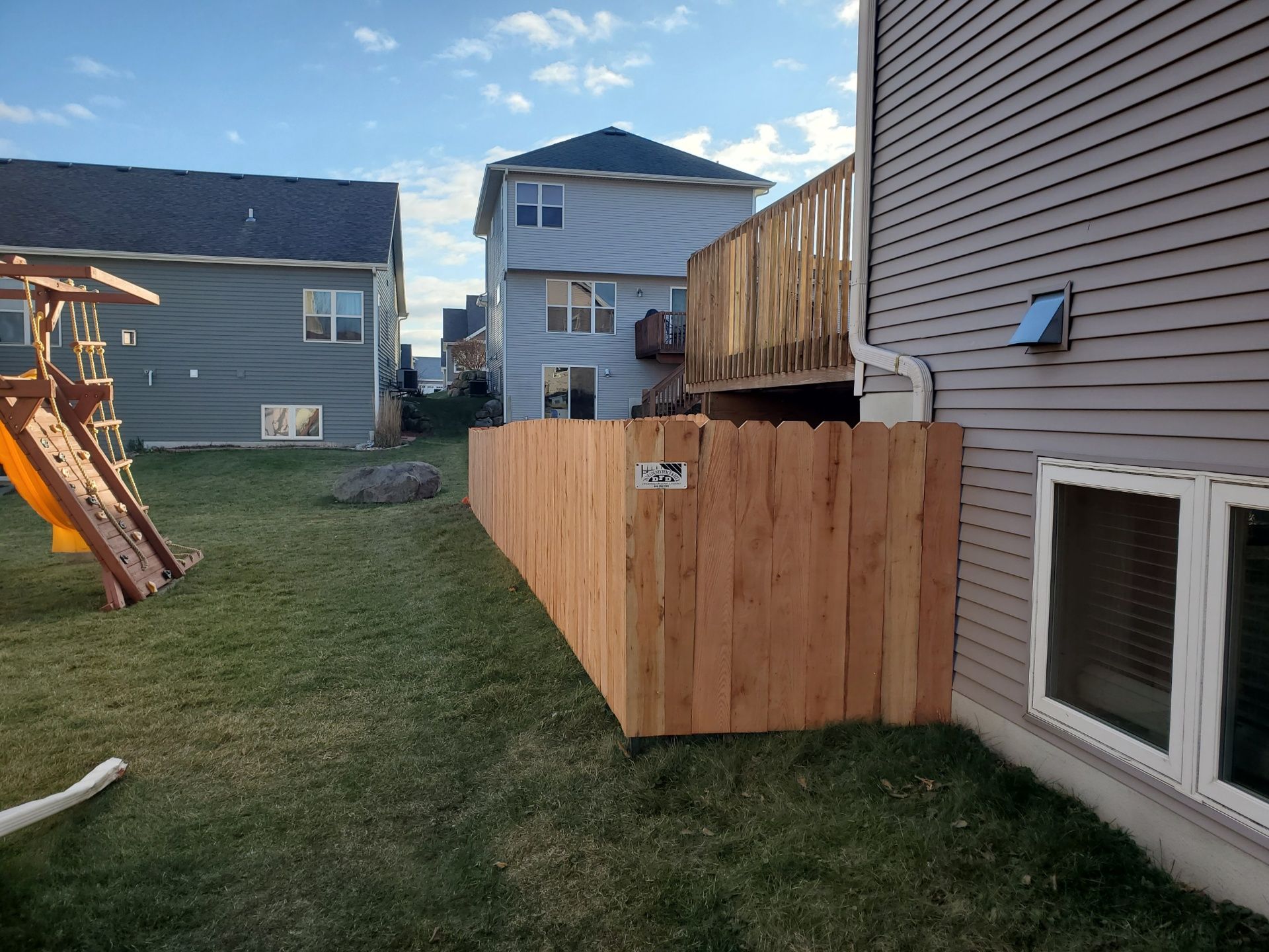 A wooden fence is in the backyard of a house.