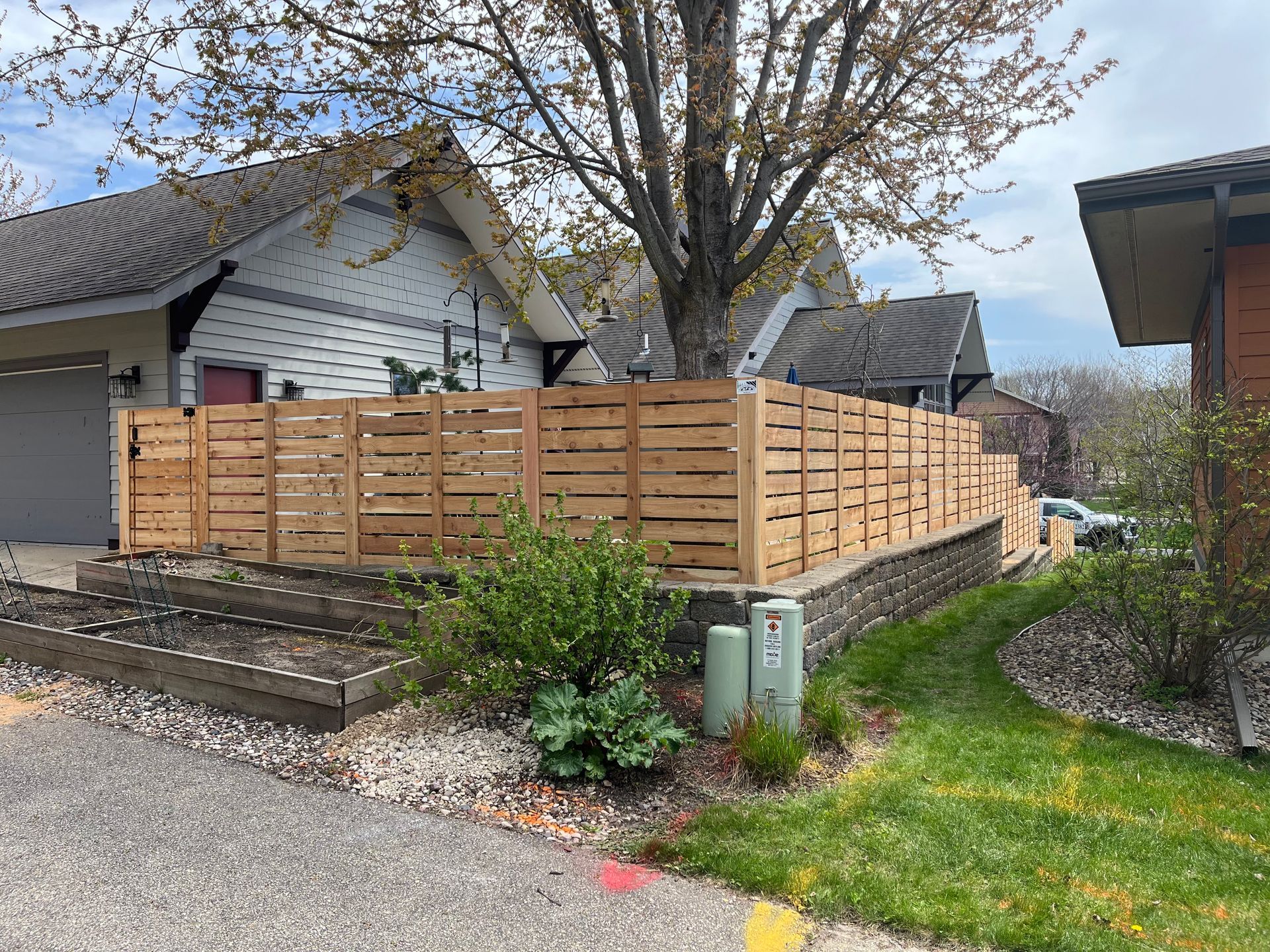 A wooden fence is surrounding a house in a residential area.