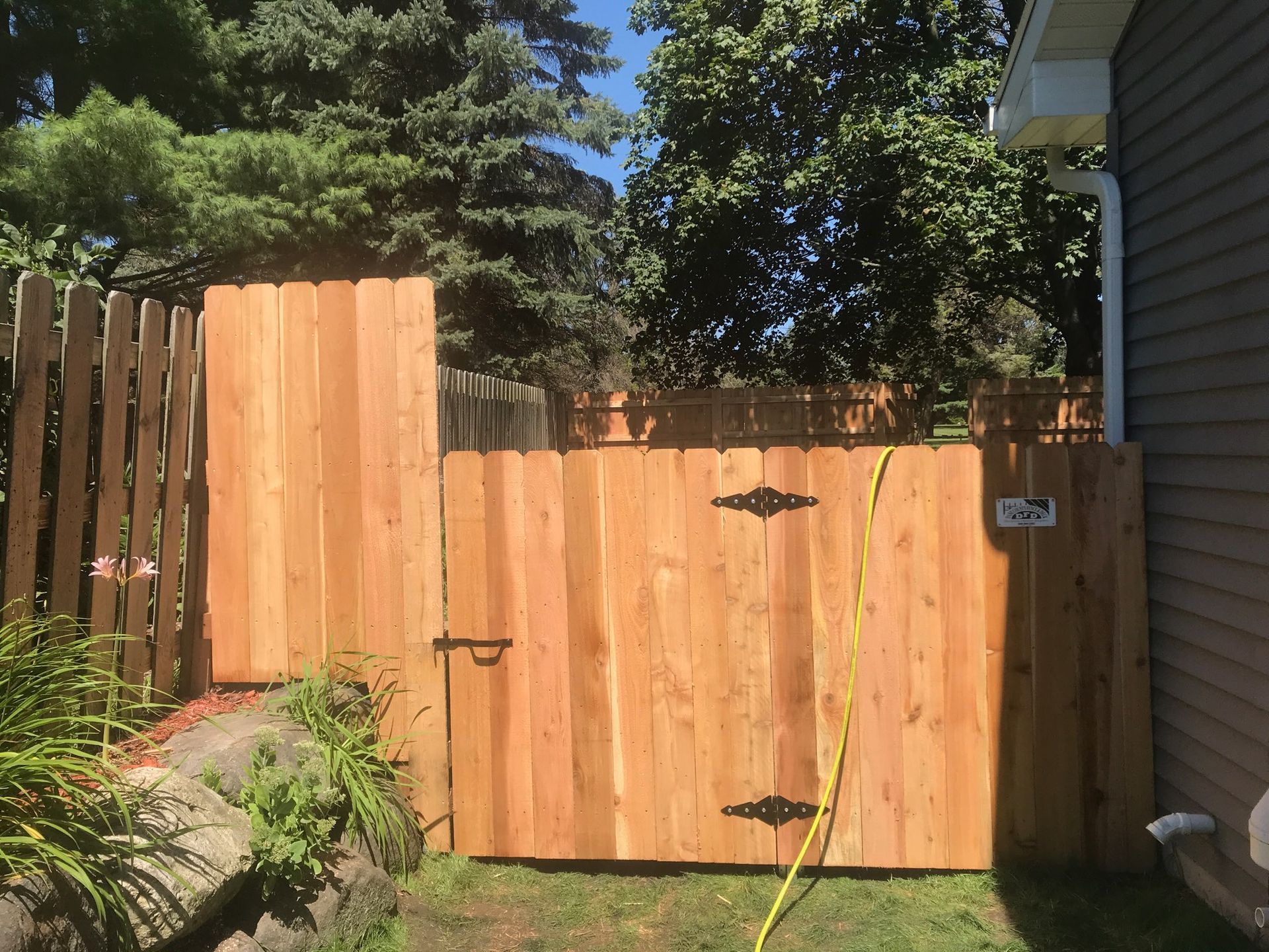 A wooden fence with a gate and a house in the background