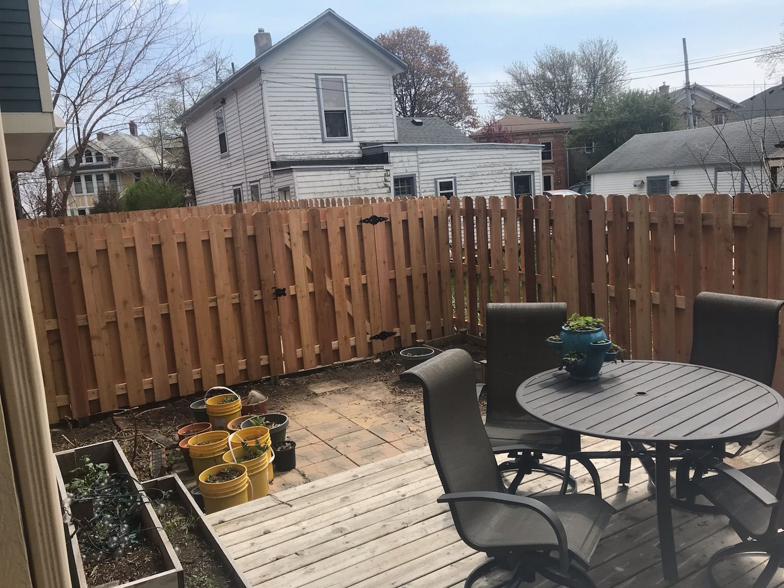 A wooden fence surrounds a patio with a table and chairs.