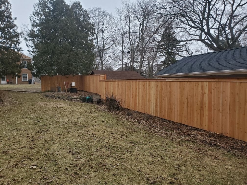 There is a wooden fence in the backyard of a house.
