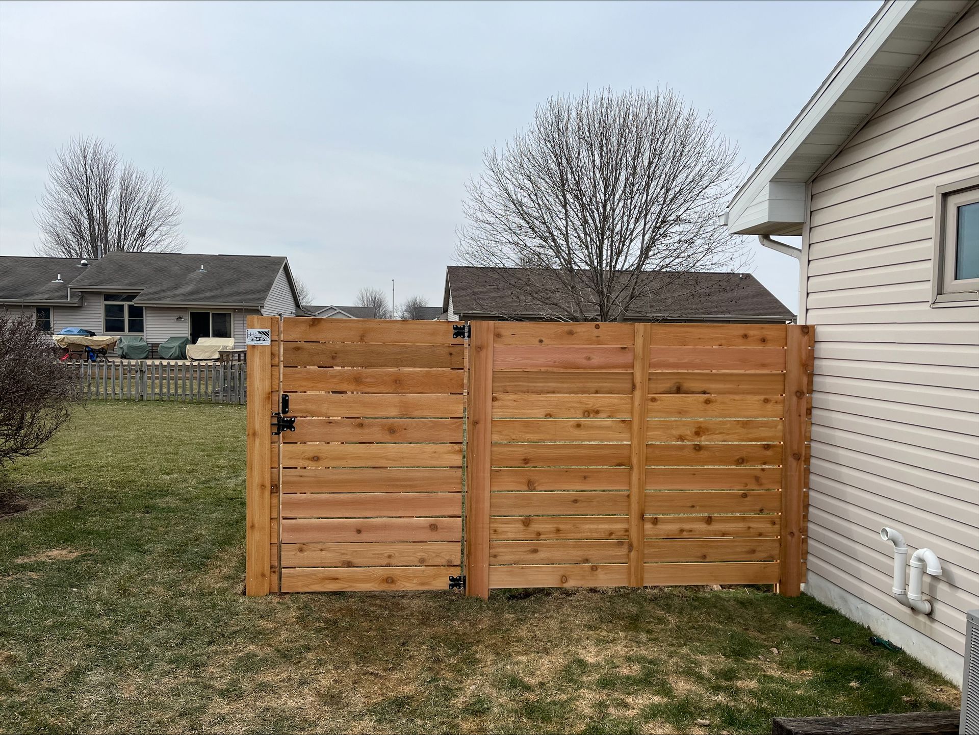 A wooden fence is in the backyard of a house.