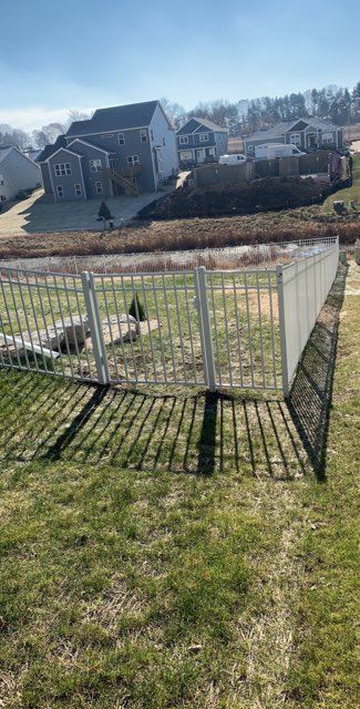 A white fence is sitting in the middle of a lush green field.
