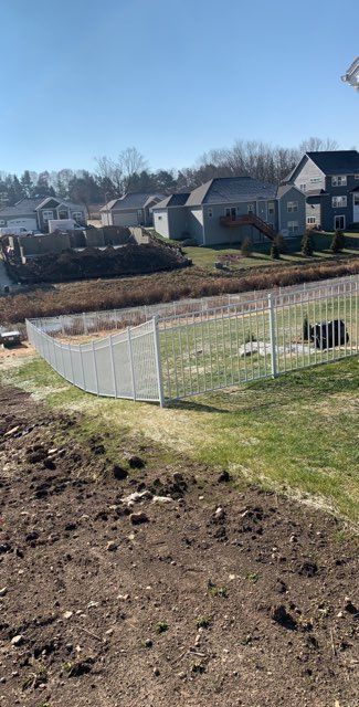 A white fence surrounds a lush green field in a residential area.