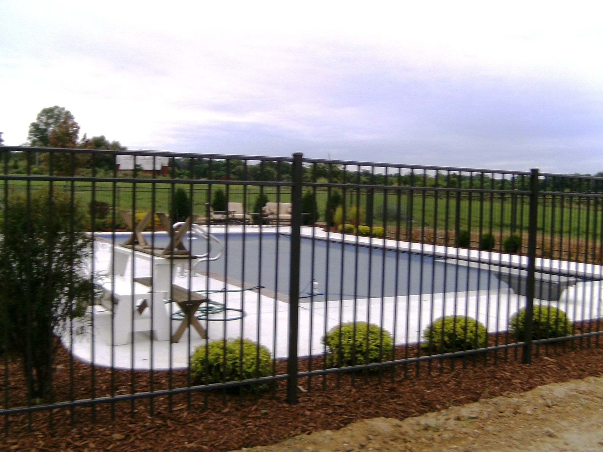 A metal fence surrounds a large swimming pool