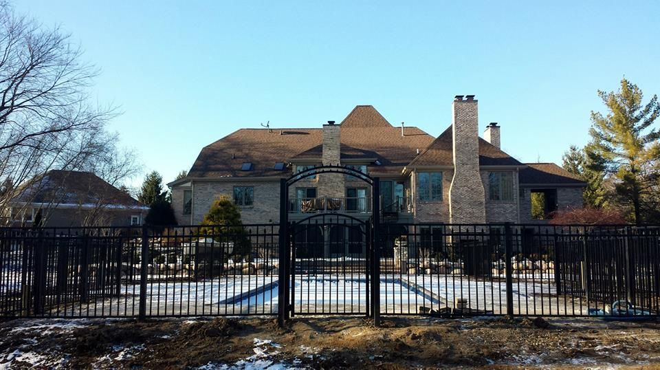 A large house with a fence around it and a pool in front of it.