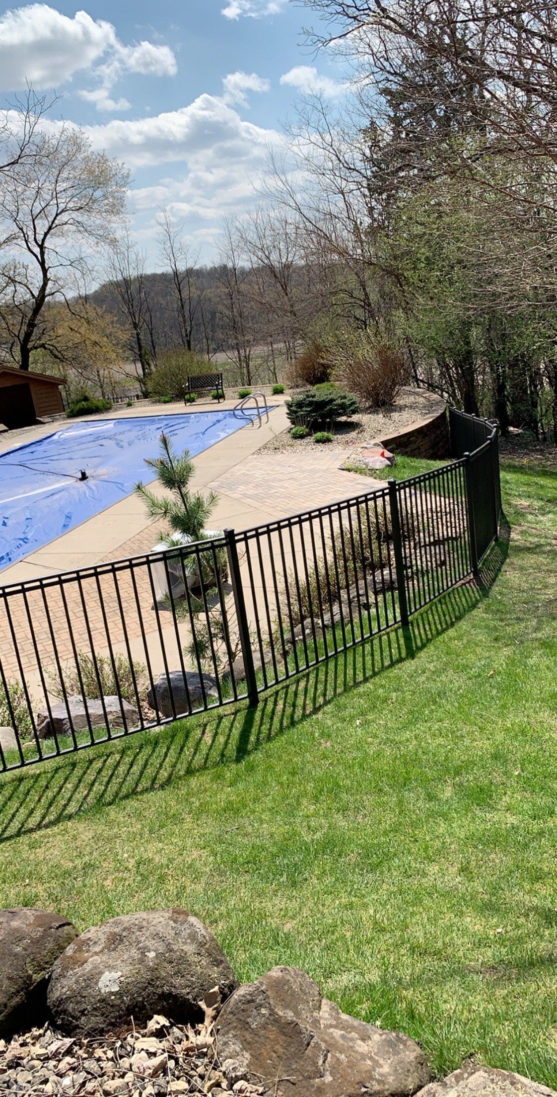 A fence surrounds a swimming pool in a backyard.